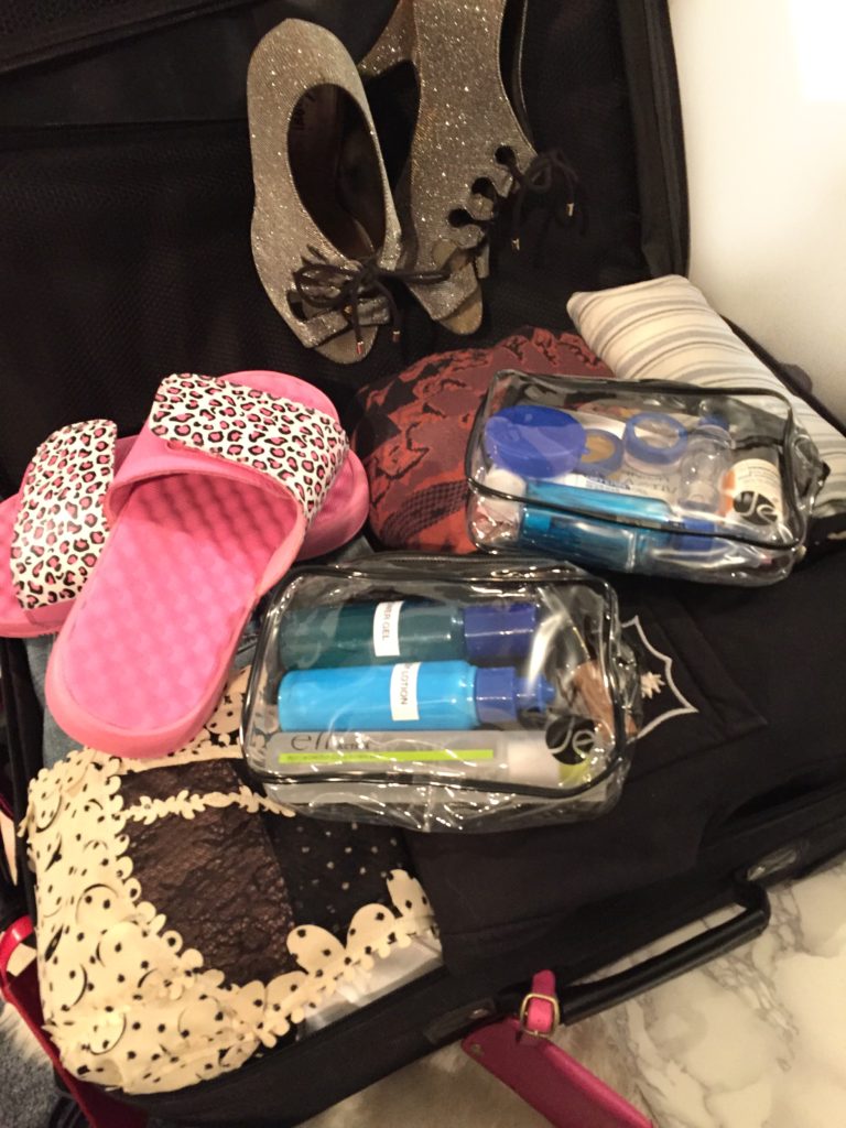 Carry-on suitcase packed with clothes and beauty products, how to pack a carryon